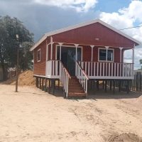 Log home elevated on stilts with staircase and veranda